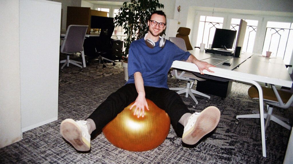 A man sitting on a pilates ball in an office