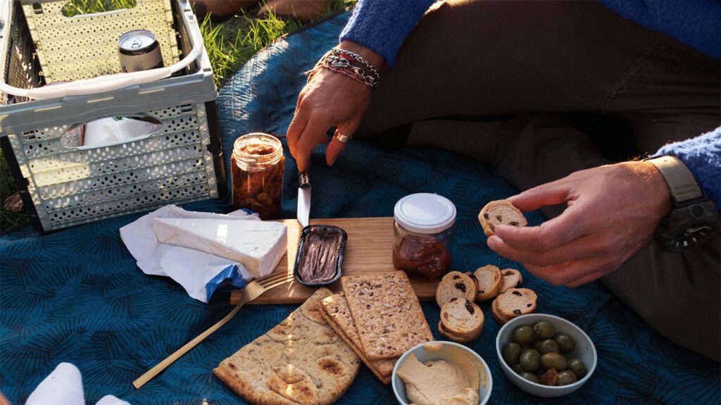 A person getting ready to spread a range of jams, marmalades, and spreads onto a piece of crostini and various crackers