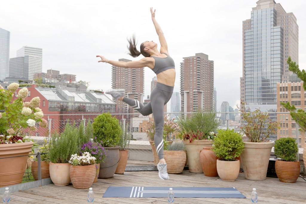 Megan Roup posing during the Tory Burch Rooftop Workout at New York Fashion Week, jumping in the air