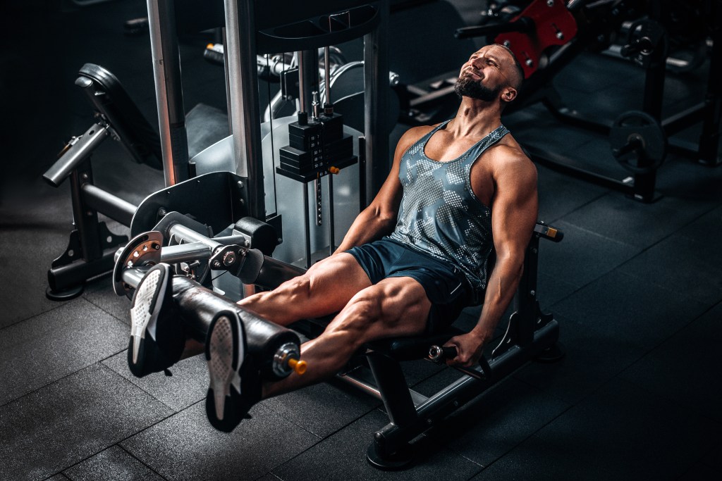 Muscular man working hard using a leg weights machine at the gym