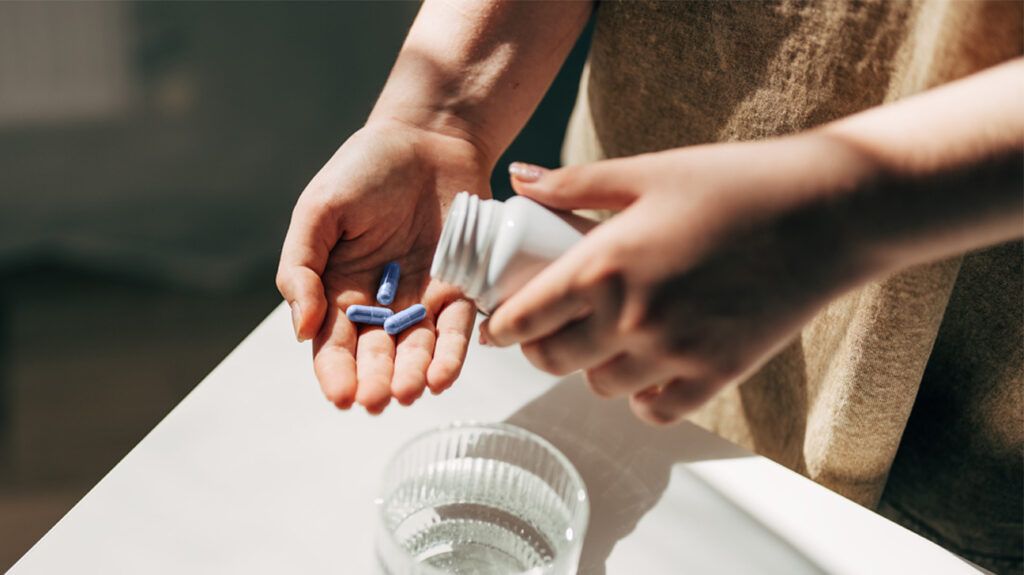 person pouring blue pills into hand