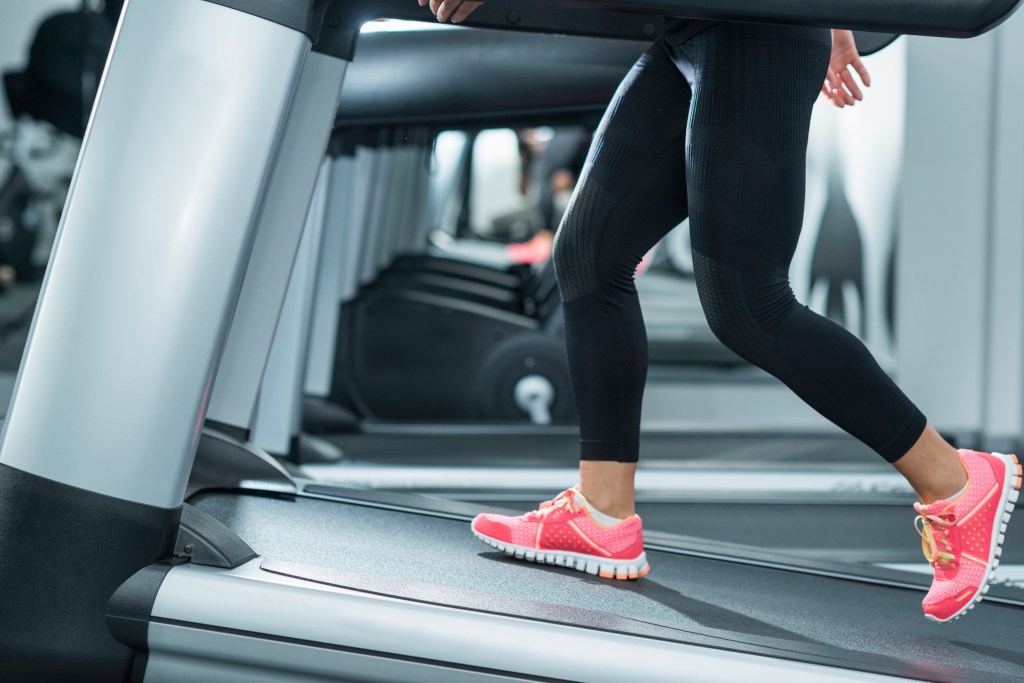 Woman in black yoga pants using an incline treadmill in a modern gym