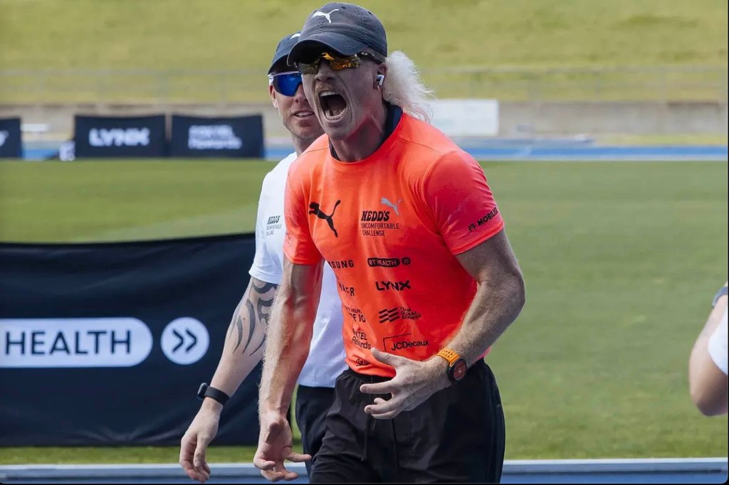 Man with long hair wearing a hat and orange shirt, possibly Nedd Brockmann, expressing intense emotion