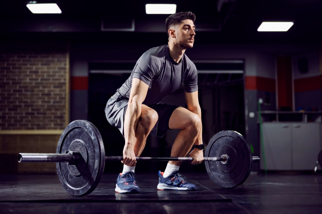 Fit sportsman performing a deadlift exercise in a gym