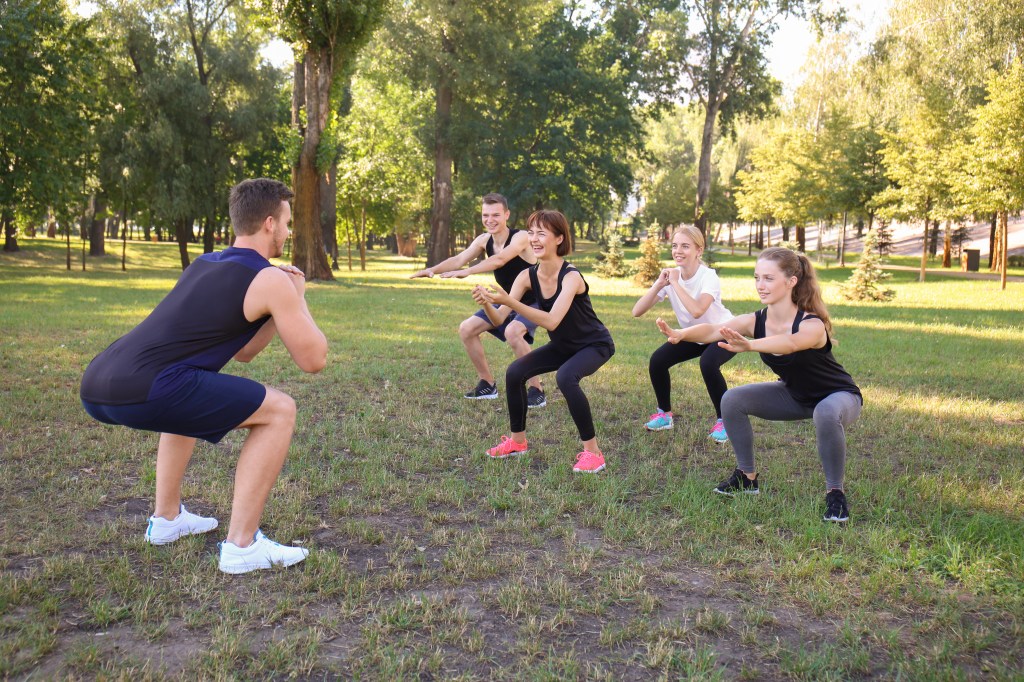 Squatting with an improper form can lead to knee cartilage injuries. You may want to consult with an exercise professional. Here, a trainer leads a class in squats.