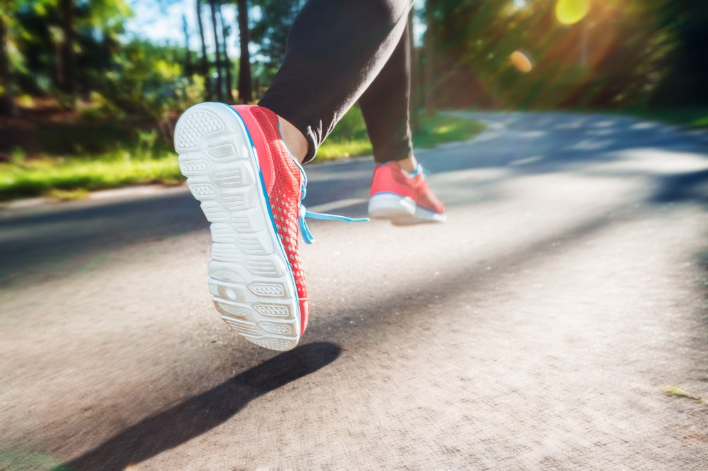 Woman in red shoes jogging on an outdoor trail at sunset