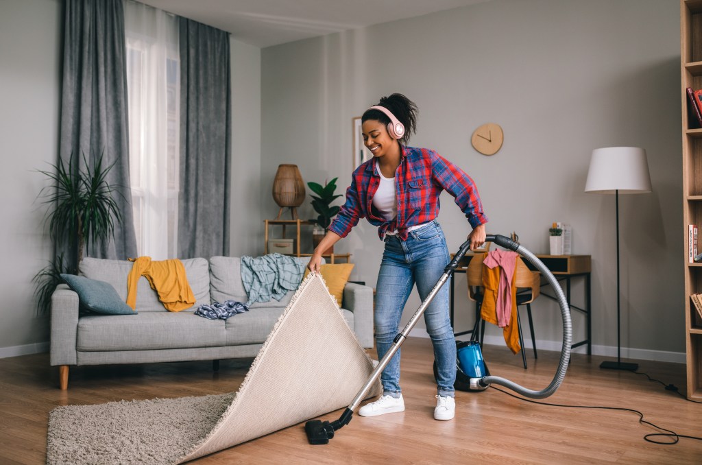 Woman vacuuming under a rug