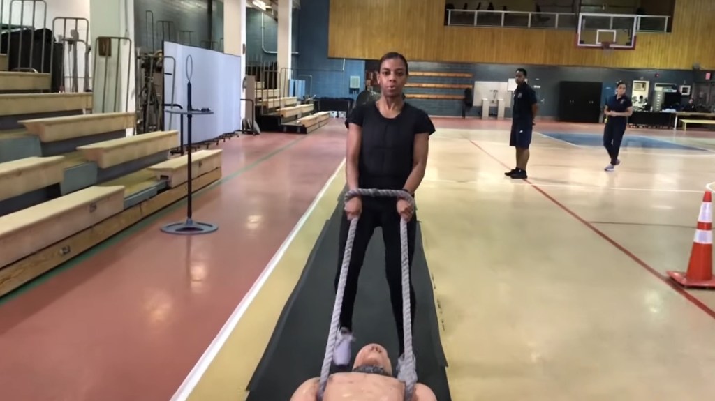 Police academy recruit dragging a mannequin as part of the NYPD's physical fitness test.